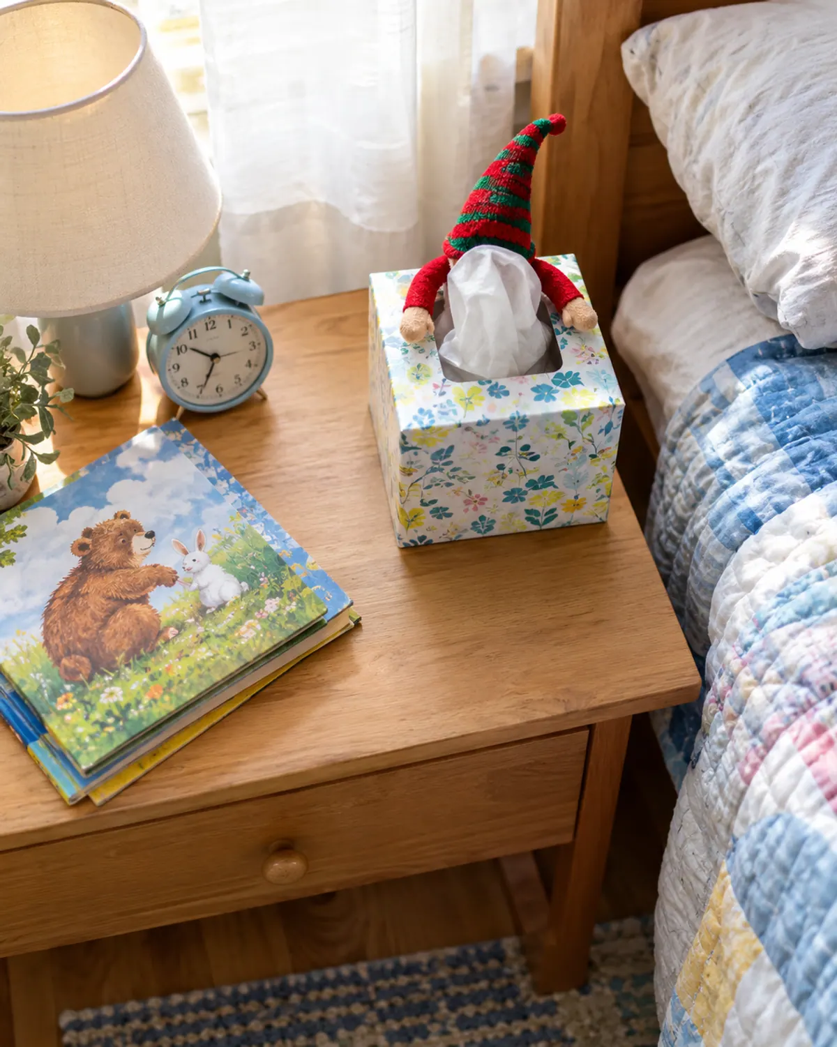 Easy elf on the shelf idea: a felt elf peeks out of a tissue box on a bedside table, only its striped hat and arms showing